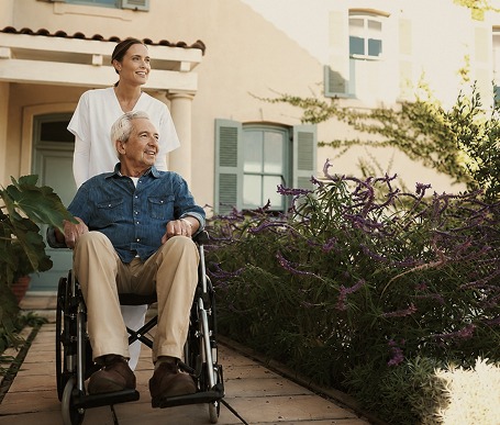 Caretaker pushing person in wheelchair