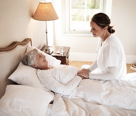 Caretaker helping person in bed